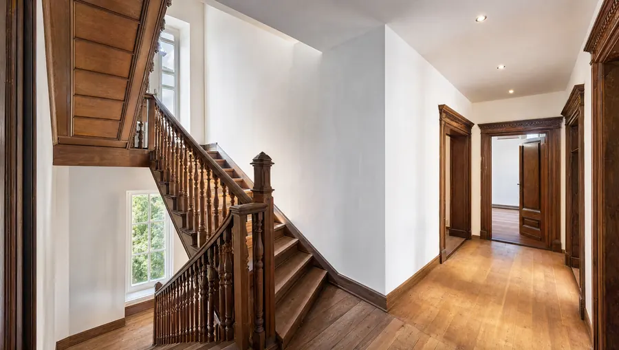 Sanierter Altbau-Treppenflur mit aufgearbeiteter Holztreppe und frisch verputzten Wänden